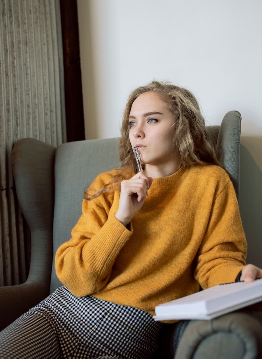 Femme en pull rouge assise devant une table et regardant sur le côté