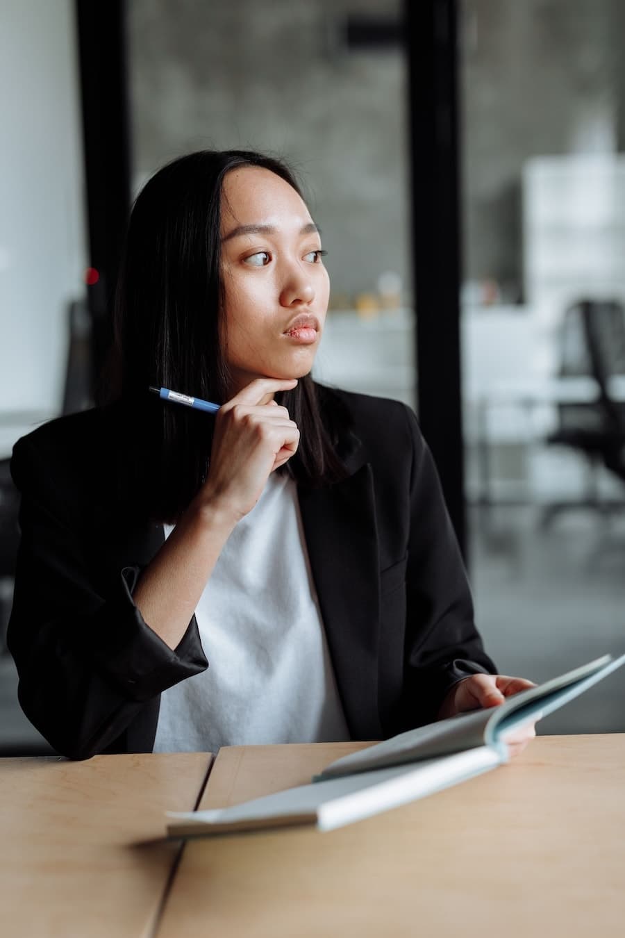 Femme assise à un bureau, un stylo à la main devant un carnet ouvert