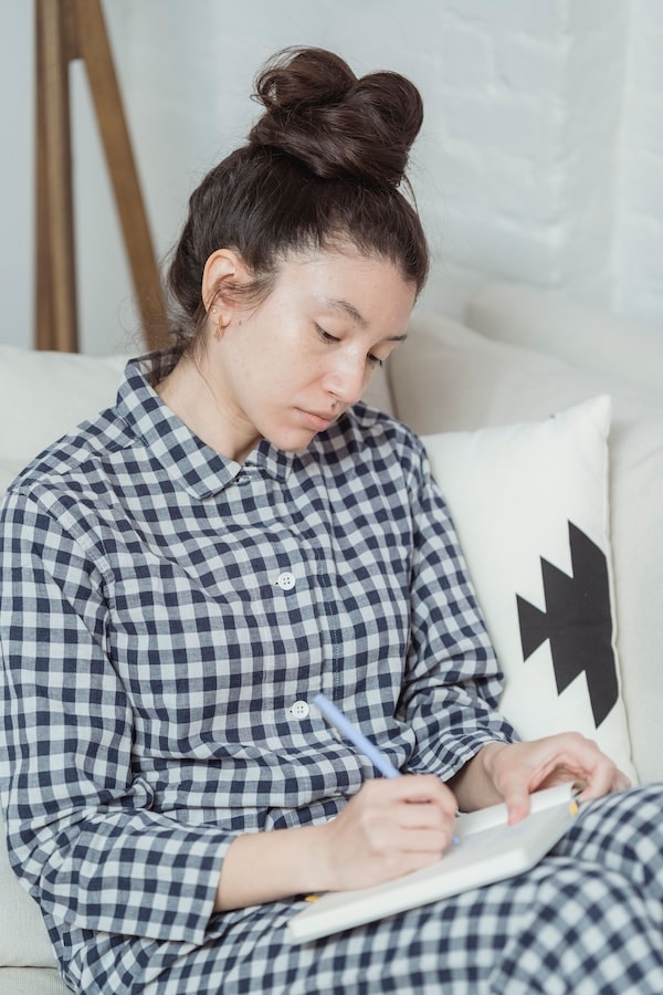 Femme en chemise à carreaux dessinant dans un carnet